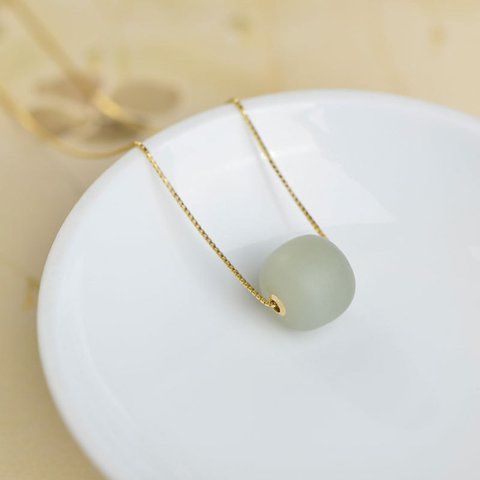 Close-up of the round Qiemo jade pendant encased in gold sterling silver frame