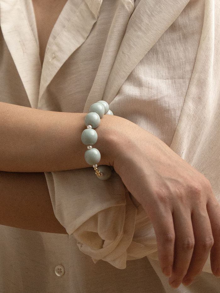 Wrist view of model wearing the bracelet with relaxed posture, showing the smooth ceramic sheen and proportional fit.