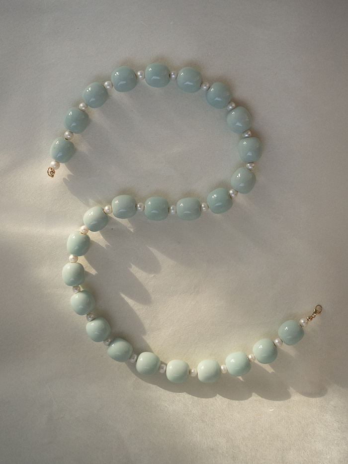Natural light shot of the necklace in soft wave shape, casting subtle porcelain reflections.