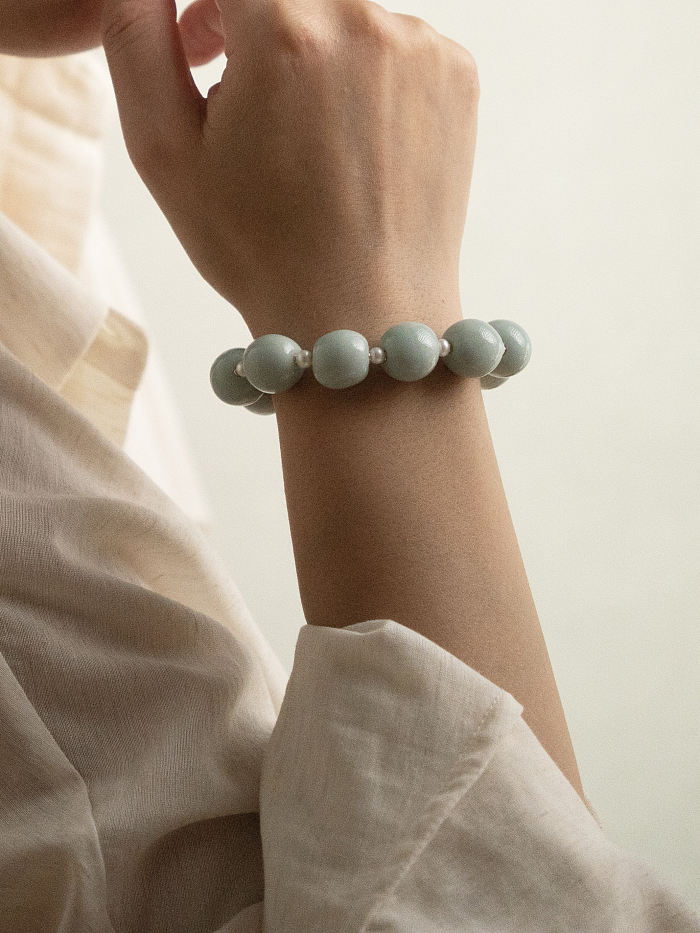 Close-up of bracelet on wrist, highlighting the sculptural round beads and subtle contrast between porcelain and pearls.