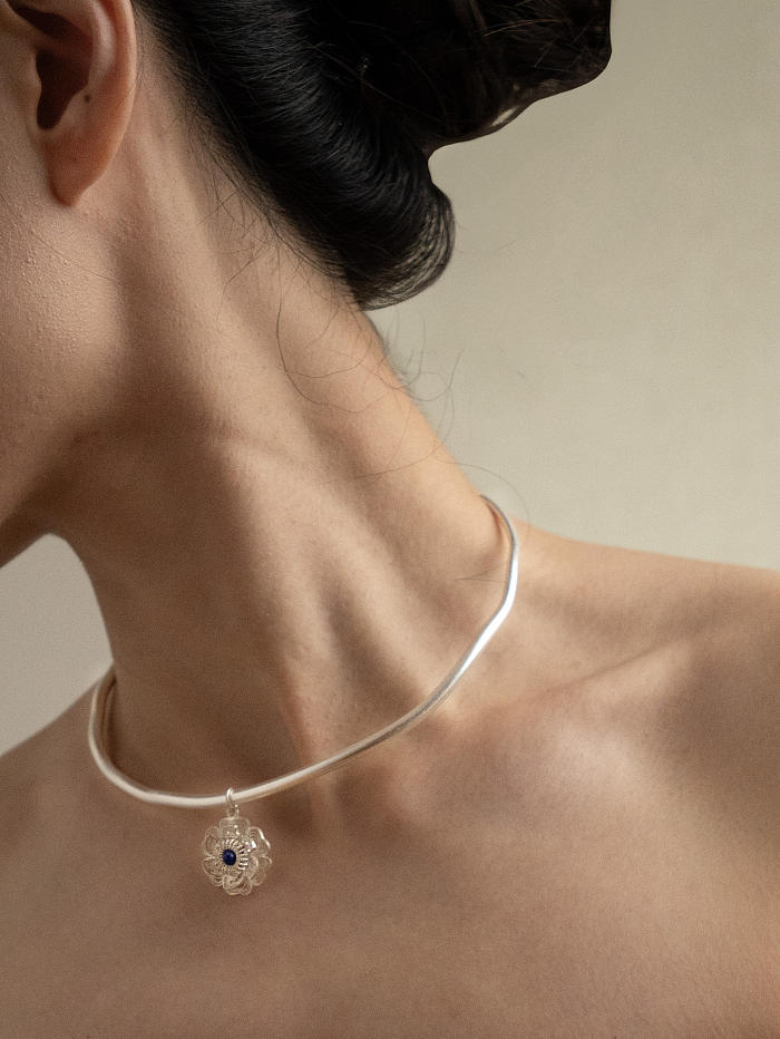 Side view of necklace on model with lapis-set pendant and sculptural neckline form