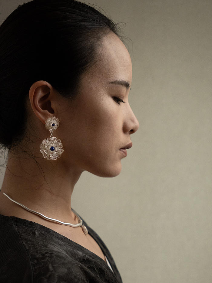 Front profile of model wearing Huasi Twin Bloom Earrings in soft directional light