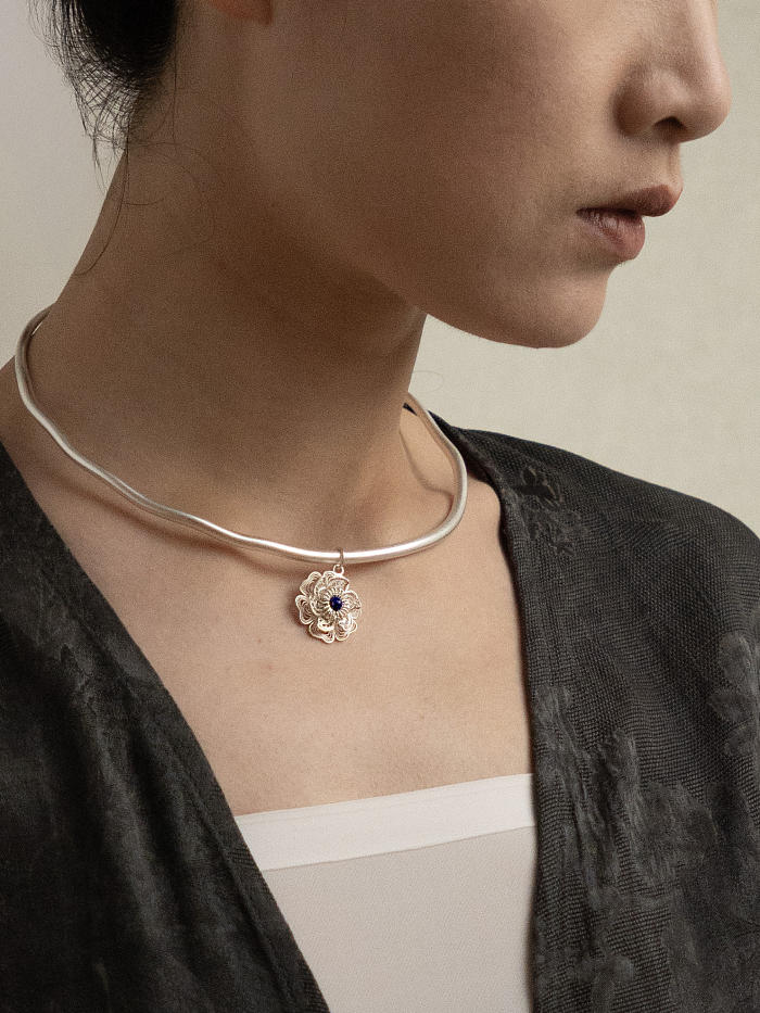 Model in black outfit wearing collar necklace, highlighting proportion and central bloom