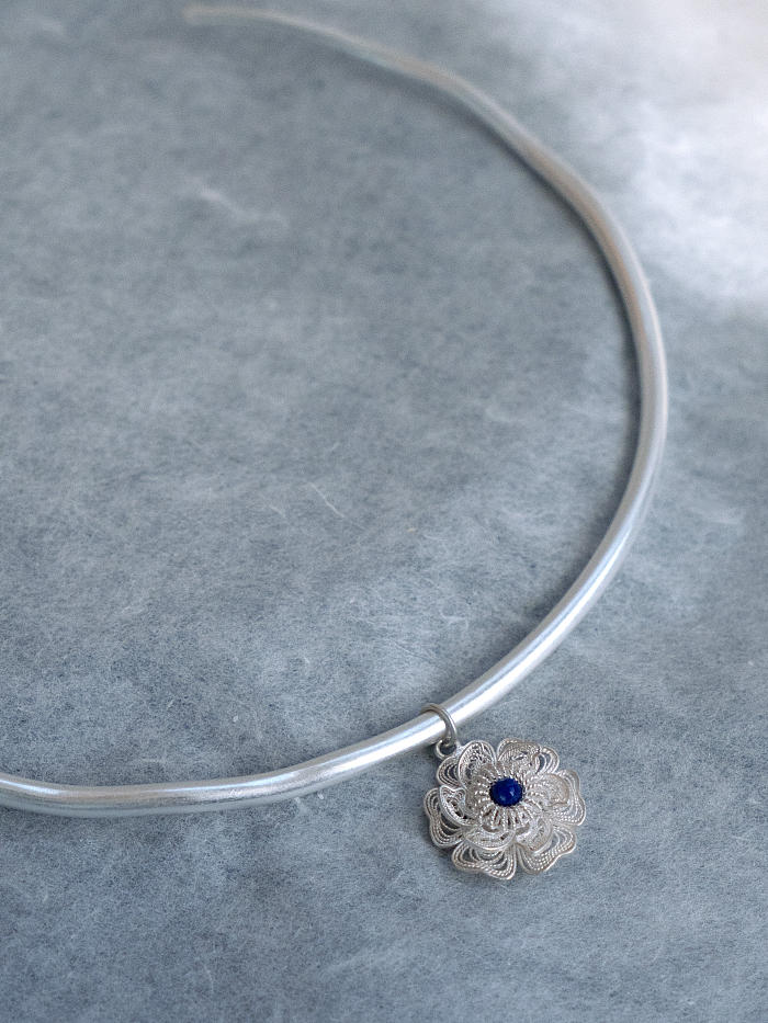 Angled top-down view of necklace, capturing flower detail and subtle arc of the collar