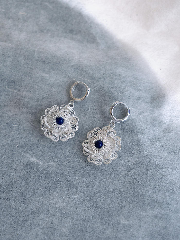 Flatlay of earrings side-by-side, showing bloom structure and polished hoop details